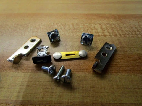 Contact Kit With All The Essentials Parts And Accessories For 15000001 Easy Install And Quick Fixes Plug And Play Setup For Smooth Operation And Reliable Performance. metal contact kit parts and screws on wooden surface