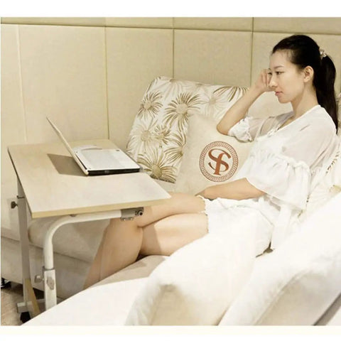 Sleek Rolling Laptop Desk With Locking Casters And Adjustable Tilt Tray Table For Home Office Bedroom Couch Computer Stand Fast Setup Portable Workspace Game Changer White 60X40 is next to a woman sitting on a couch.