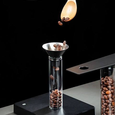 Glass Coffee Bean Storage Tubes Set Of Six With One Way Degassing Valve And Magnetic Stand And Single Dose Espresso Dosing Vials To Keep Your Java Fresh As A Daisy While Handling Your Essential Daily Grind Session, showcasing funnel pouring beans.