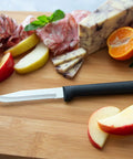 Built Tough Serrated Paring Knife Duo Featuring Premium High Carbon Stainless Steel Blades That Tear Through Tough Fruit And Veggie Skins Without A Sweat With Sleek Black Handles Pack Of Two on a wooden cutting board with sliced fruits.
