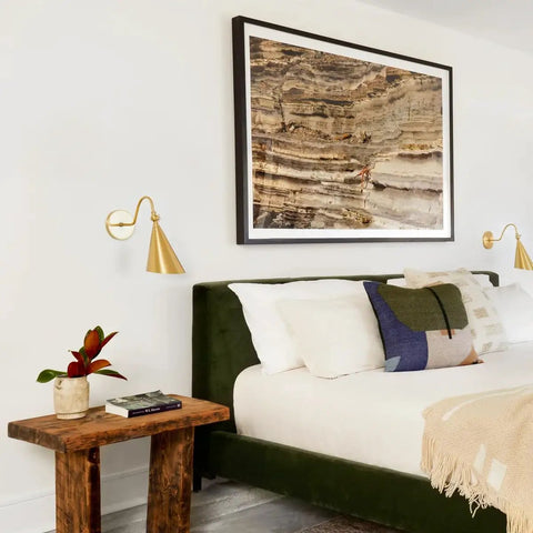 Lupe Wall Sconce Brass With Perforated Shade And Bowtie Swivel in bedroom with painting above bed, cozy ambience