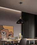Black Industrial Metal Pendant Light, E26 Curvy Adjustable Ceiling Fixture hanging over a modern dining table with artistic decor.
