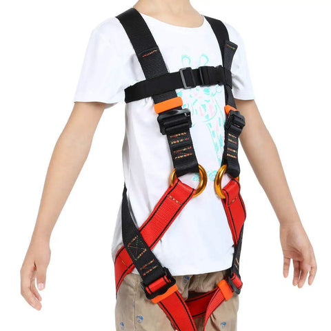 Kid wearing full body safety harness for outdoor adventures built tough for tree climbing zipline caving and rappelling fun training.