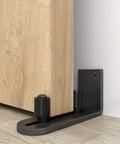 Sliding Barn Door Floor Guides Adjustable Stay Roller Hardware Kit Set of 2 with Smooth Ball Bearings and Flat Bottom Design Flush With Floor Wall Mount Roller Guide for Small Space Black Sturdy Steel Bracket and Upgraded Round Corners installed on wood floor.