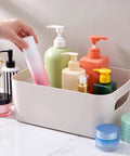 Gray White Plastic Storage Bins With Reinforced Handles For Home Organization And Closet Pantry Use Stackable Small Containers holding various bottles.