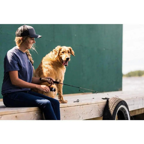Person fishing with Dock Runner Spinning Reel And Fishing Rod Combo 36 Inch Medium Action Multi Piece Rod beside a dog on a dock