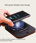 Person placing a smartphone on a Solidly Built Wireless Charging Mug Warmer And Desk Phone Base With Auto Shut Off Keeps Your Morning Brew Piping Hot While You Charge On The Fly In Classic Black.