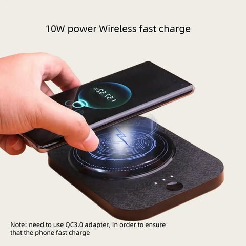 Person placing a smartphone on a Solidly Built Wireless Charging Mug Warmer And Desk Phone Base With Auto Shut Off Keeps Your Morning Brew Piping Hot While You Charge On The Fly In Classic Black.