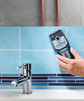 Hand using Wall Scanner For Studs Metal And Live Wiring With Center Finder Multi Mode Detection near tiles and pipes
