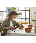 Person using Top Shelf Rotary Tool Accessory Kit Loaded With Heavy Duty Micro Bits for carving wooden bowl shapes at a table.