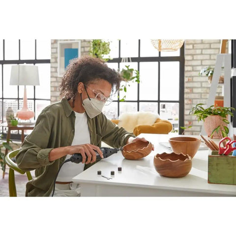 Person using Top Shelf Rotary Tool Accessory Kit Loaded With Heavy Duty Micro Bits for carving wooden bowl shapes at a table.