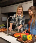 Two women using a Heavy Duty Flow Max RV Water Pump With 50 PSI Pressure and 3 GPM Flow in a modern kitchen.