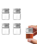 Four Pack 5ml Glass Jars With Lids Tiny Mini Bottles For DIY Crafts Storage And Decor Screw Cap Containers shown with a hand holding one