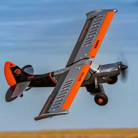 Micro Scrappy 800mm RC Airplane BNF Basic With Flaps And LED Navigation Lights in flight, orange and black design.
