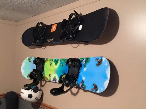 Rock Solid Aluminum Wall Mount Snowboard Rack With Hella Secure Eva Grip Pads To Keep Your Boards Locked Down Safe For Garage Or Home Storage Layouts Includes Two Heavy Duty Rack Units holding two snowboards on a wall.