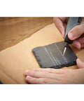Person using 8 Piece Glass And Stone Accessory Micro Kit for carving lines on a dark slate tile, demonstrating engraving capability.