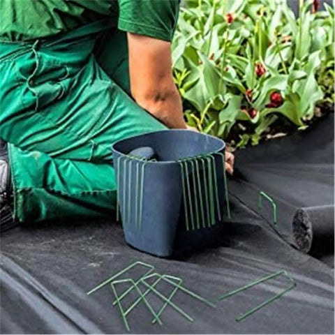 Person installing Heavy Duty Garden Ground Stakes 6 Inch U Shaped Steel Pegs For Lawn Fabric Netting Matting Pro Grade Landscape Anchors 20 Pack