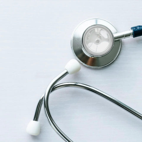 Angled front view of a stethoscope with silver chest piece and white ear tips