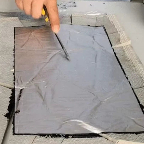 Heavy Duty Waterproof Roof Tape being cut with scissors on a countertop, Asphalt material for sealing leaks.