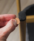 Hand applying 3 8 inch round self adhesive felt furniture pad to a cabinet leg for protection against scratches.