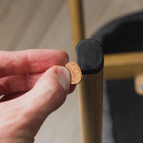 Hand applying 3 8 inch round self adhesive felt furniture pad to a cabinet leg for protection against scratches.