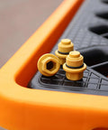Close-up of Heavy Duty Spill Proof Oil Tank Containment Tray Set For Warehouses And Shops with yellow drain plugs on black surface.