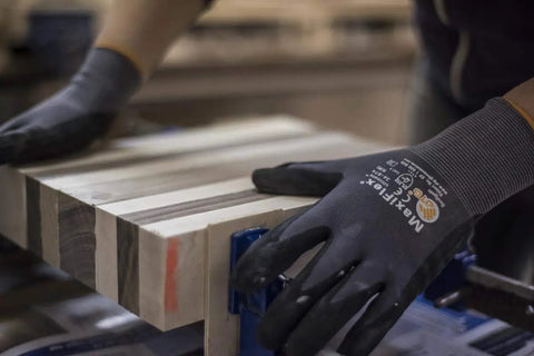 Person wearing 3 Pack Nitrile Grip Work Gloves X-Small Size, handling wood with abrasion-resistant snug form-fit for construction