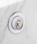White Silicone Drain Plug Stopper with Ring for Bathtubs and Sinks installed in a marble bathtub, featuring a metal hanging ring.