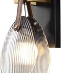 Fluted Glass Wall Sconce Ribbed Shade Leather Strap Brass Finish Metal Light 10 Inch Height mounted on wall for bedroom or hallway use.