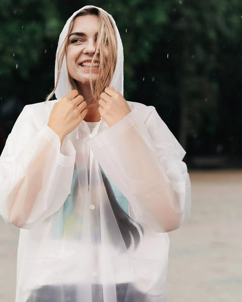 Woman in clear poncho from 14 Pack Reusable EVA Rain Ponchos for Adults with Drawstring Hoods Waterproof Rain Gear for Women and Men