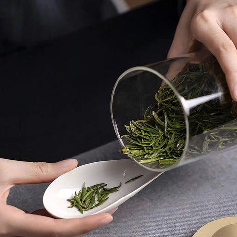Top Notch Slick Large Glass Kitchen Jars Set Of Four Aluminum Lids with tea leaves pouring into a spoon for organized storage.
