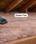 Hand holding a Solid As A Rock Spring Steel Insulation Support Wire 16 Inch in attic insulation for secure placement.