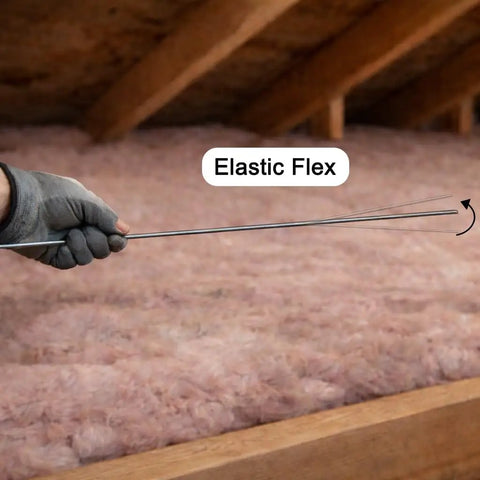 Hand holding a Solid As A Rock Spring Steel Insulation Support Wire 16 Inch in attic insulation for secure placement.