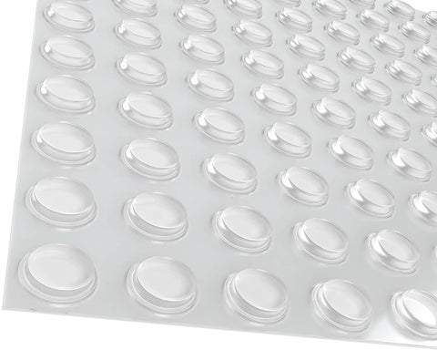 Close-up of Clear 100 Pack Cabinet Door Bumpers With Adhesive Pads Half Inch Diameter on sheet, transparent round cushions.