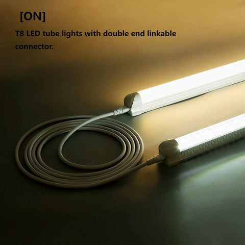 10ft Female to Female Extension Cords for LED Tubes T5 T8, coiled on surface with T8 tube lights illuminated, double end connectors.