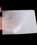 Hand holding single Foam Cushioning Pouches Pro Grade Pack Of 100 Full Coverage EPE Pearl Cotton Wrap for Fragile Items and Cups