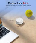 Compact mini carbon monoxide detector on a desk near a laptop, supporting household safety with UL certification.