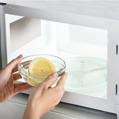 Person placing bowl with lemon slices in microwave showing installed 10 Pack Microwave Waveguide Covers Mica Sheets