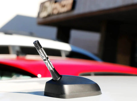 Gloss black Union Jack 3-inch antenna topper on MINI Cooper, exterior upgrade with UK flag style in sunlight