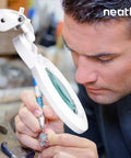 Man using XL Bifocals 1200 Lumens LED Magnifying Lamp With Clamp for detailed jewelry work at a desk.