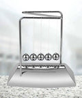 Z Shape Newton's Cradle Pendulum Balls For Learning And Home Office Decoration on a desk, five silver balls swinging.