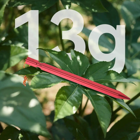 Ultralight 7-Inch Aluminum Tent Stakes Set 12 Pack With Reflective Pull Ropes, shown on foliage, highlighting 13g weight.