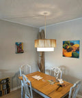 18 Inch Plug In Rattan Pendant Light With Premium Linen Shade Boho Ceiling Chandelier over dining table in rustic room setting.