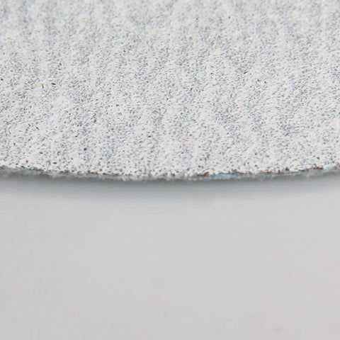 Close-up of 7 inch aluminum oxide sanding disc showing the textured surface for Grab These 50 Pack Super Tough 7 Inch Aluminum Oxide Sanding Discs With Hook Loop Backing And Flocking Design For Smooth Dry Sanding Projects No Clog Needed.