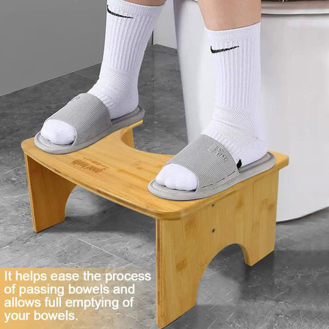 Person using foldable bamboo toilet stool for adults, 7.5 inch squat aid, collapsible poop stool with non slip strip in bathroom