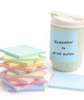 Pastel Sticky Notes 3 By 3 Inch 12 Pack With 50 Sheets Per Pad stacked next to a mug with a note reminding to drink water.