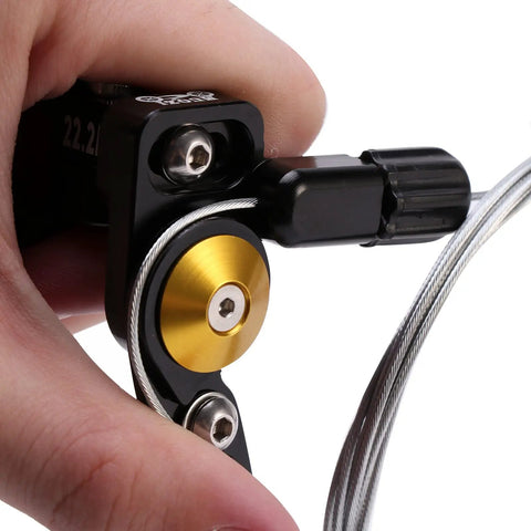Hand holding Universal MTB Dropper Remote Lever For 22.2mm Or 24mm Handlebar, showing cable and black aluminum components.