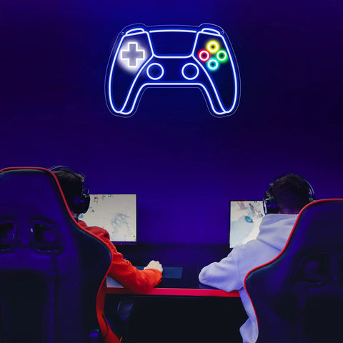 Gamepad Shaped LED Neon Sign for Gaming Room Decor illuminated on a wall above two gaming setups with chairs, creating a vibrant atmosphere.