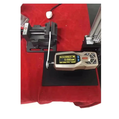 Slick Handheld Digital Surface Roughness Tester Portable Profilometer measuring Ra Rz on a black surface with a vice.