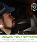 Side view of man wearing Bump Cap Safety Hat With Reflective Stripes Baseball Cap Style Hard Hat in a dark workspace